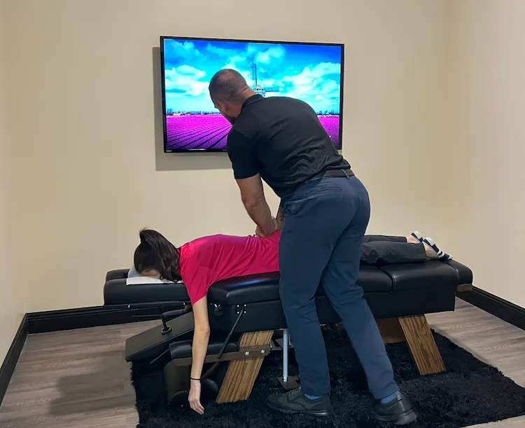 Chiropractor adjusting the lower back of a woman lying face down on a chiropractic table.