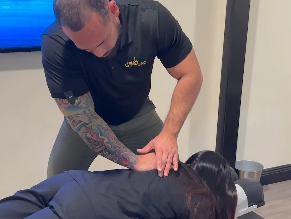 Chiropractor adjusting the mid back of a woman lying face down on a chiropractic table.
