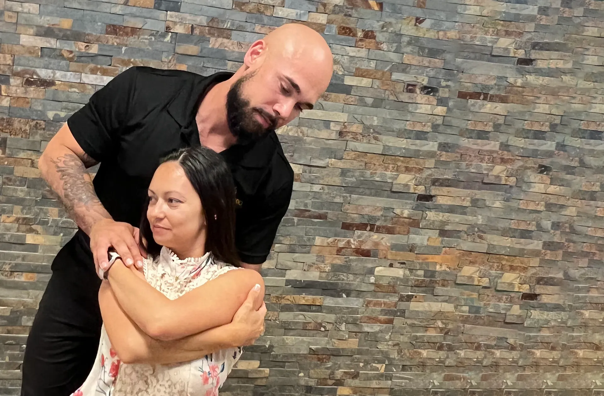 Dr. Junior positioning a seated woman with her arms crossed for an upper back adjustment.
