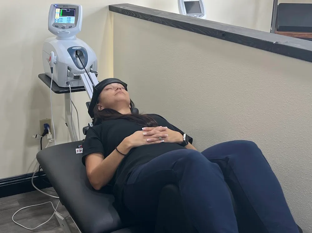 Woman relaxing with hands folded while her neck rests in a cervical traction unit.