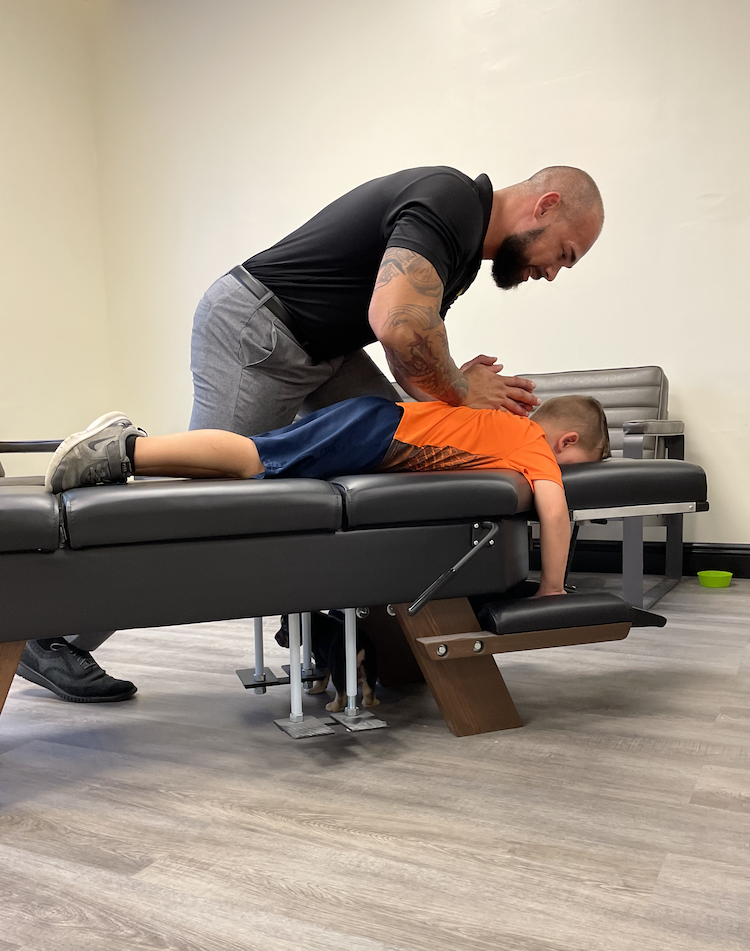 Dr. Isidoro Acevedo Jr giving kid pediatric chiropractic care treatment